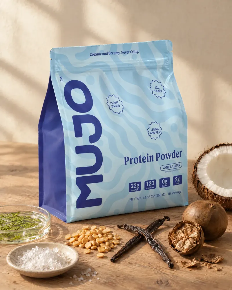 A standing pouch of Mujo Protein Powder with Lemna leaf, yellow peas, vanilla, coconut and monk fruit arranged around it.